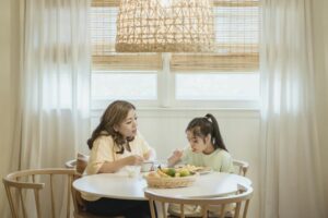 A mother and daughter sharing a breakfast meal at a cozy home dining table.